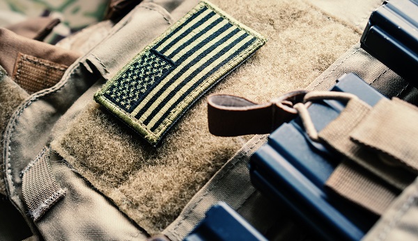 Green US flag patch on the tactical bulletproof vest with M4 magazines, selective focus